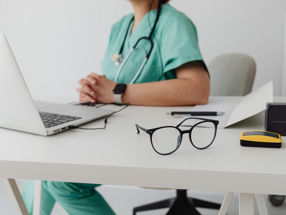 Profesional sanitaria en su consulta, con un portátil sobre la mesa